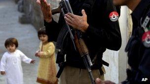 Police officers stand guard outside the house of Kainat Riaz