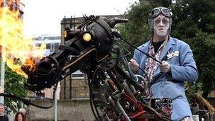 Man dressed in ghoulish costume on a metal horse sculpture