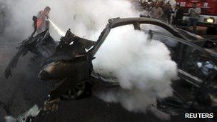 A man extinguishes the fire in a car targeted by an Israeli air strike in Gaza City