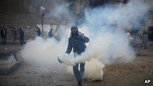 A protester throws a tear gas canister away near the interior ministry during clashes with the Egyptian riot police, not seen, in downtown Cairo, Egypt, Sunday, Nov. 20, 2011