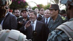 In this Sunday, 6 Aug 2012 image, Egyptian President Mohammed Mursi, centre, and Field Marshal Gen Hussein Tantawi, right, visit soldiers in Egypt's northern Sinai Peninsula