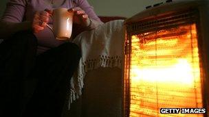 Pensioner in front of heater