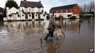 A man wheels his bike through floodwaters in Tewkesbury