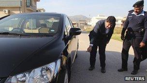 Senior journalist for the Geo News television station Hamid Mir points to his car where a bomb was found underneath, in Islamabad November 26, 2012.