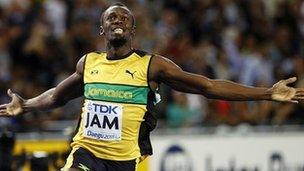 Usain Bolt sprinting in a yellow vest. His arms are stretched out to his sides in celebration.