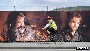 Man cycles past sign board in Wellington, New Zealand, advertising The Hobbit, on 27 November 2012