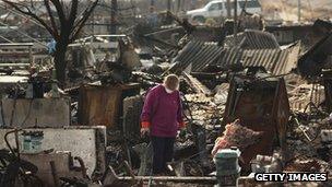 A woman goes through debris where her home used to stand in Breezy Point, New York 4 December 2012