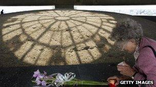 A woman lights a candle next to the ashes, purported to be from victims of the Majdanek Nazi death (file image from 2004)