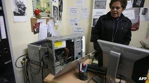 A woman looks at a computer with a missing hard-drive inside the offices of Addameer in Ramallah (11 December 2012)