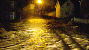 Water pouring through street in Llanfair Talhaiarn during flooding in November 2012