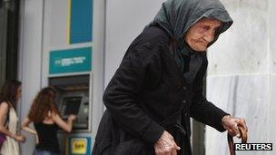 An elderly woman walks past an ATM machine in Athens. Photo: May 2012