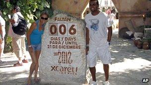 Tourists get their picture taken next to a slab of stone counting down the days until Dec. 21, 2012 at the Xcaret theme park in Playa del Carmen, Mexico