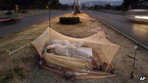 Labourers sleep under a mosquito net in the middle of a road in Islamabad, Pakistan, June 2012