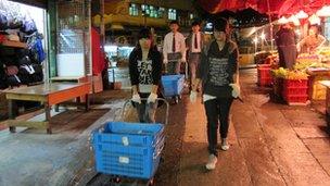 Students carrying baskets of discarded vegetables