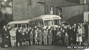 People standing near a bus in the 1950s