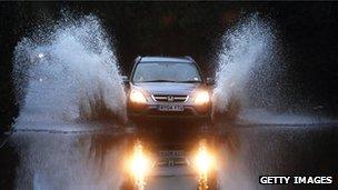 A vehicle drives through flood waters from the River Thames in Sonning, England