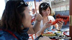 Two women eat Lobster outdoors