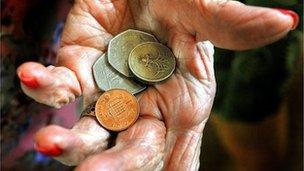 Elderly hand holding coins