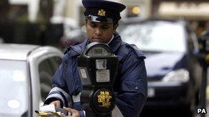 Traffic warden checking parking meters in central London