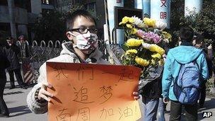 Unidentified man wearing a mask with word "silent" holds a banner reading: "Let's chase our dreams together, go Southern Weekly newspaper" during a protest outside the newspaper on 7 Jan 2013