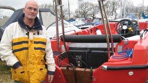 Poole Sailability volunteer instructor Phil Berry inspects the damaged boat