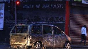 A burnt out car blocks a road in east Belfast