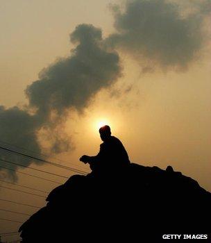 Man sitting on coal sacks at a Chinese power station (Getty Images)