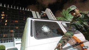 A Libyan security officer points to the damage of the bullet-proof vehicle in which Italy's consul to Benghazi was riding