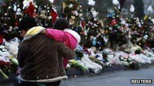 A woman holds a child next to a makeshift memorial for victims who died in the December 14 shootings at Sandy Hook Elementary School, in Newtown, Connecticut December 18,