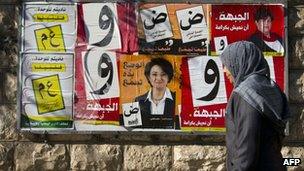 Woman walks past campaign poster for Israeli Arab candidates