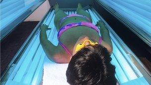 Person tanning in a sunbed unit