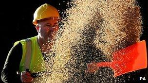 A council worker shovels rocksalts as he waits to have his gritting lorry reloaded