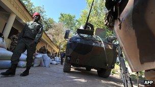 A Malian soldier walks past French military vehicles in the city of Niono