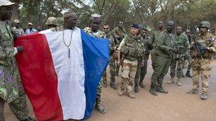 This handout picture taken on January 19, 2013 and released on January 22, 2013 by the French Army Communications Audiovisual office (ECPAD) shows French and Malian soldiers standing next to a man wearing a cloth made with the colors of the French national flag in Niono.