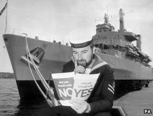 A British sailor, LREM Eric Littlehales, studies referendum leaflets while on a visit to Stockholm aboard HMS Fearless, 27 May 1975