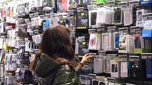 A woman in a shop in Paris looks at mobile phone accessories