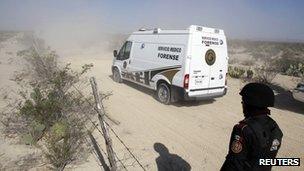 A car belonging to the forensic medical services heads towards a well where bodies were found on Monday