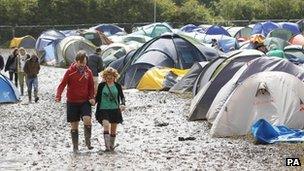 Festival-goers walk through the mud at the campsite at the Isle of Wight Festival on the Isle of Wight