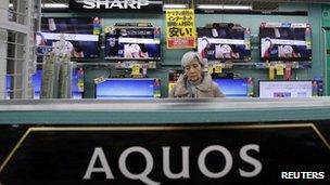 A woman looks around Sharp's TV sets at an electronic shop in Tokyo