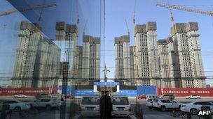 A construction site of a residential compound is reflected on the glass facades of a office building in Taiyuan, Shanxi province, 15 January 2013