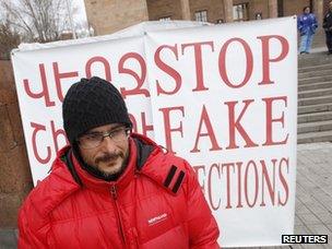 Armenian presidential candidate Andreas Ghukasyan, who has been on a hunger strike since 21 January, stands in front of a poster protesting against the election in Yerevan (17 February 2013)