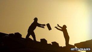 Construction workers pass bricks to each other in Phoenix, Arizona