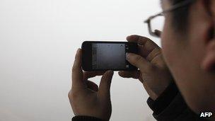 A man takes a picture with his mobile phone of the heavy smog in Qingdao, east China's Shandong province, on 29 January 2013