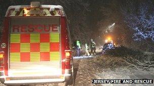 Rescue workers helping a couple trapped under a tree in Jersey