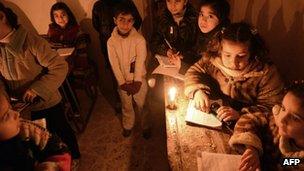 Syrian children attend an early morning class by candle light due to the lack of electricity at a school in Kadi Askar area in the northern city of Aleppo on 9 February 2013