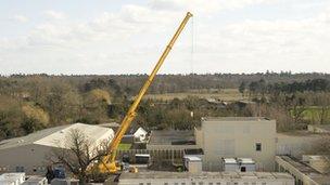 A crane lifts part of a unit into place