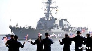 The guided missile destroyer USS Lassen (DDG 82) arrives as South Korean navy sailors wave South Korean and US flags at a South Korean naval port in Donghae, about 190km (118 miles) east of Seoul, 9 March 2013