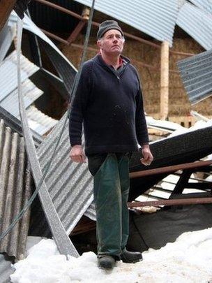 Sheep farmer James McHenry with his lambing shed, which collapsed with the weight of snow over the weekend, killing sheep and lambs at his farm in the Glens of Antrim, Northern Ireland