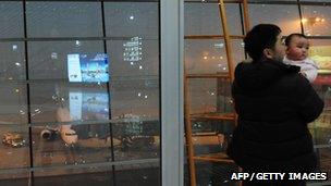 A man holds a baby inside of an airport