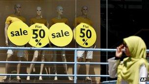 An Indian Muslim woman walks past a store offering half prize sale in Bangalore, India, Thursday, Feb. 28, 2013.